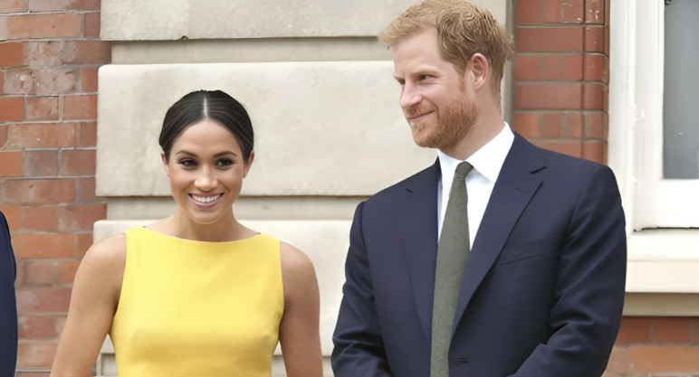 Royal Shock As Charlotte Longs For Harry’s California Life 2 Prince Harry and Meghan Markle smiling together outside a brick building, she in a yellow dress, he in a navy suit.